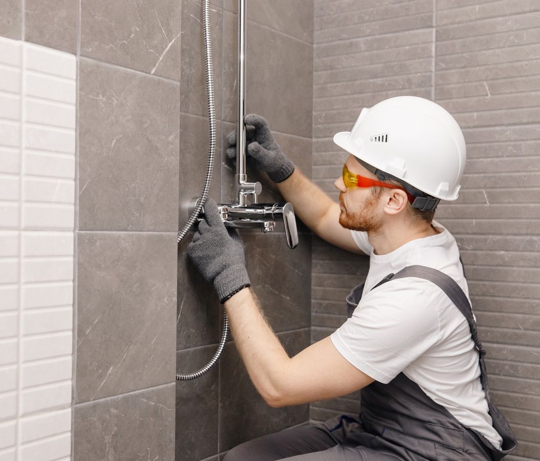 Kompetenter Sanitärtechniker schließt eine Dusche in einem modernen Badezimmer an