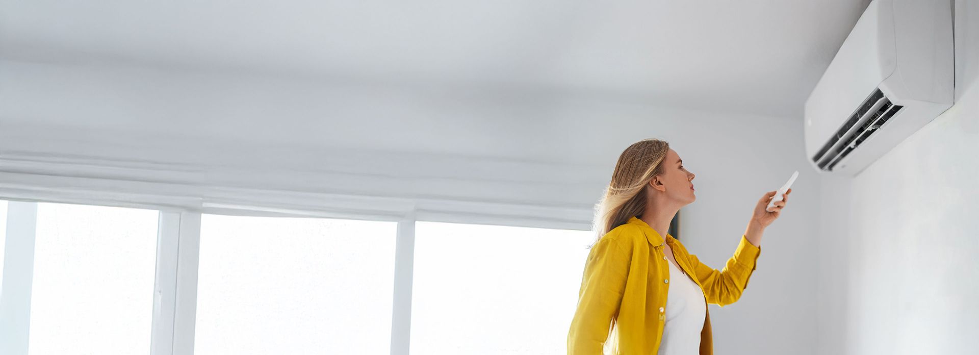 Eine Frau genießt die kühle Luft, die aus einer Klimaanlage kommt